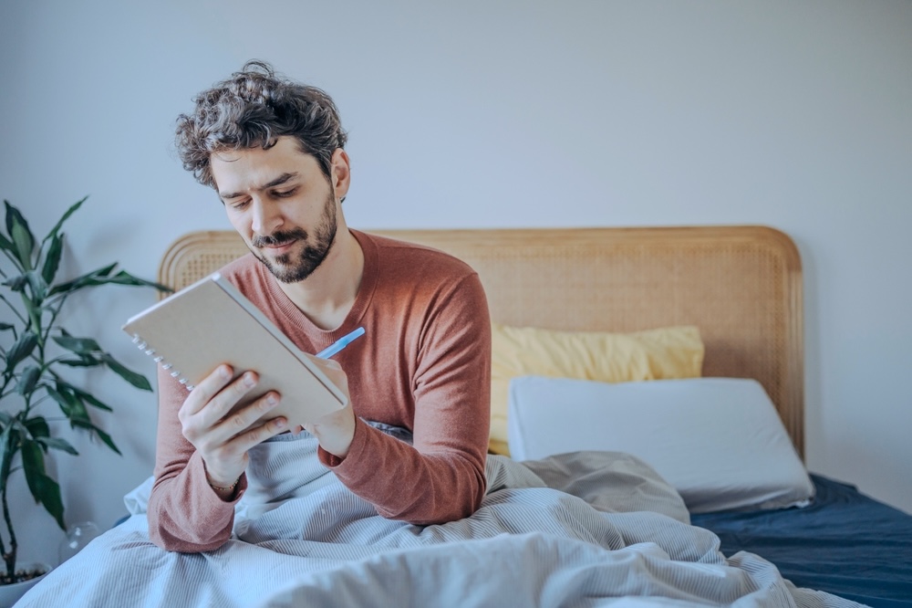 Male journaling inside a private room in a residential rehab