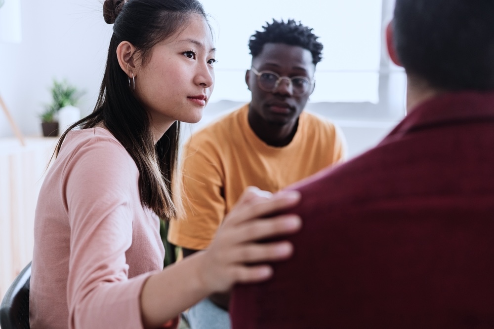 Female adult comforting another person during aftercare program inpatient rehab