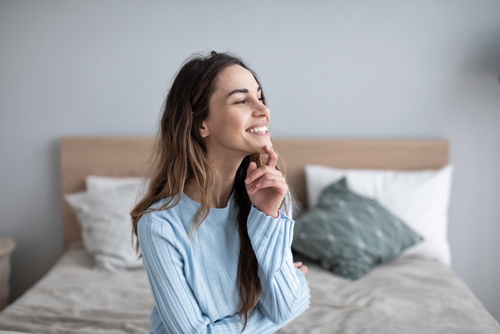 Female in blue sweater smiling while in inpatient rehab private bedroom