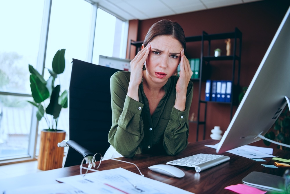 Female stressed in the office wondering how to tell her employer about going to rehab